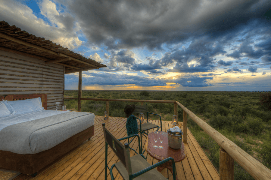 A sleepout setup in the Central Kalahari Desert featuring a simple bed on a raised platform